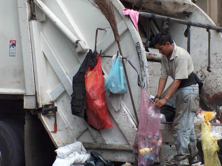 a man in an area that looks very dirty and has garbage bags hanging out the back of a dumpster