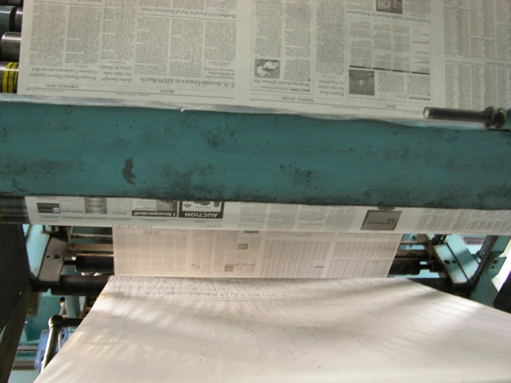 a newspaper on a paper machine near many rolls of papers