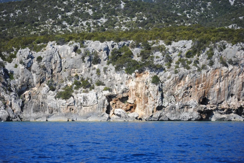 people in boats on a large body of water near some cliffs