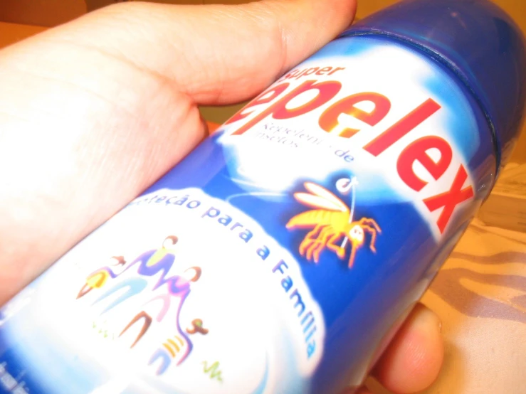 hand holding up a blue bottle with palm tree logos on it