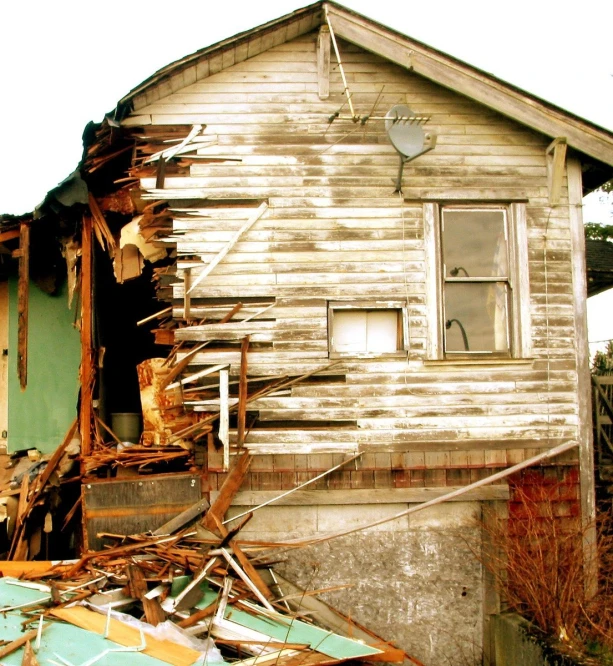 a run down wooden building with rubble in front