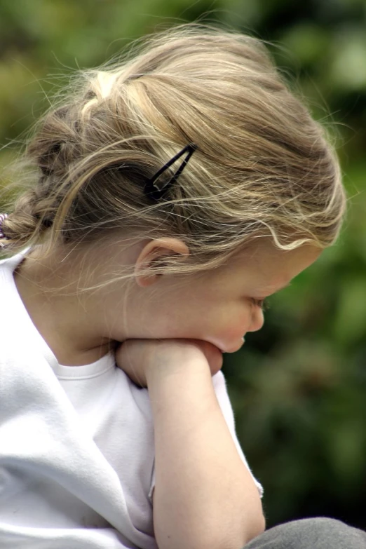 a young blonde girl is leaning against her face