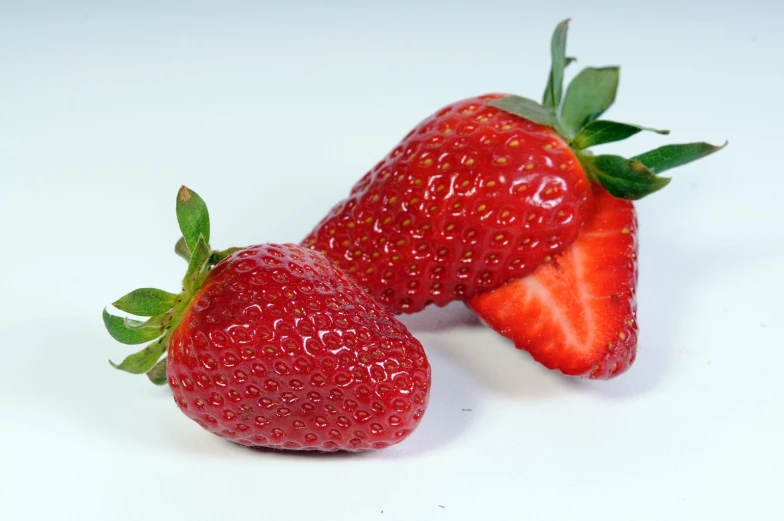 two ripe strawberries side by side against a white background