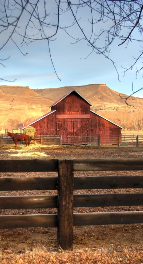 a rustic wooden fence in front of a red barn