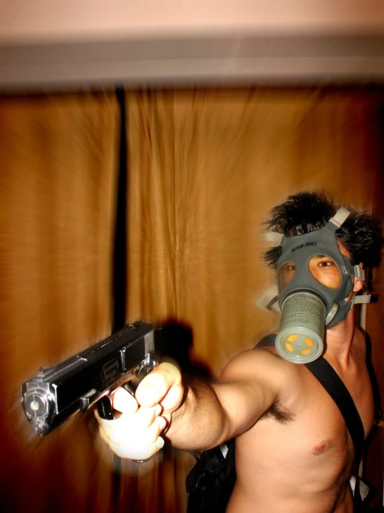 a man in gas mask pointing a gun towards the camera