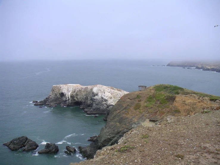 a cliff with water on it with rocks in the foreground