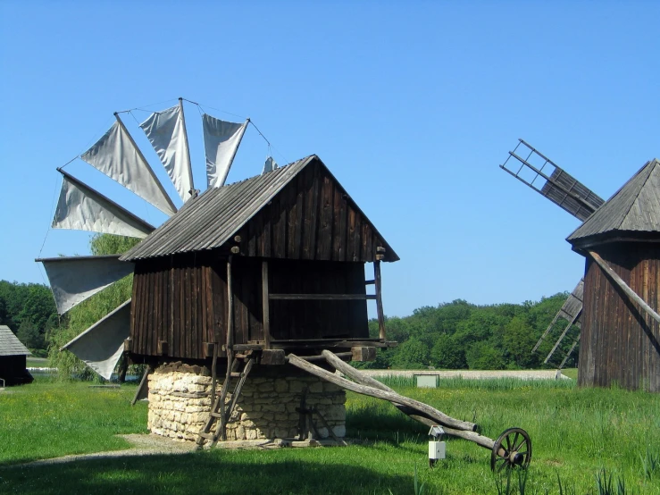 a few old windmills next to a building with sails on top