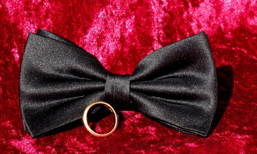 a black bow tie with an oval gold ring