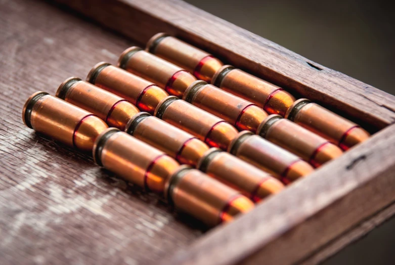 an old wood box with nine bullet cases in it