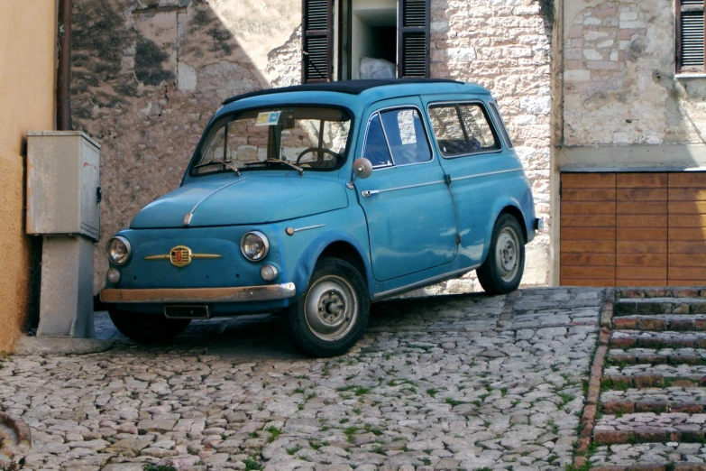 an old blue car parked in front of a house