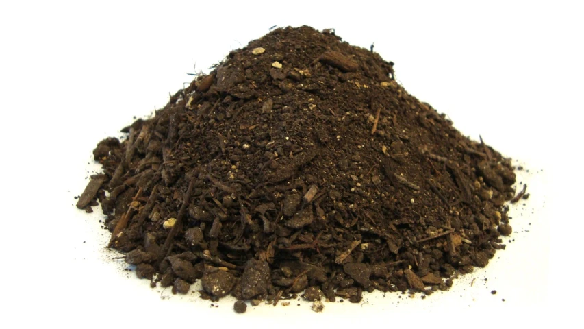 a heap of dirt next to a white surface