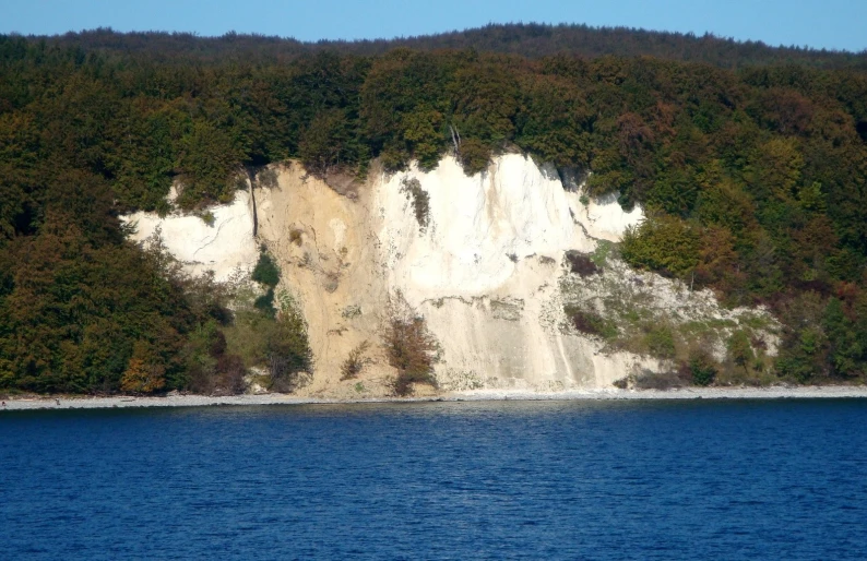 a group of white cliffs on a large body of water