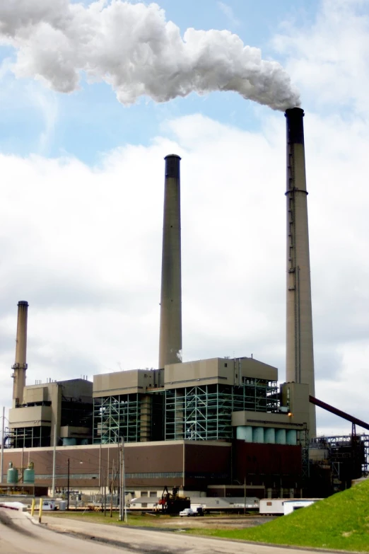 smoke pouring out of two chimneys above an industrial facility