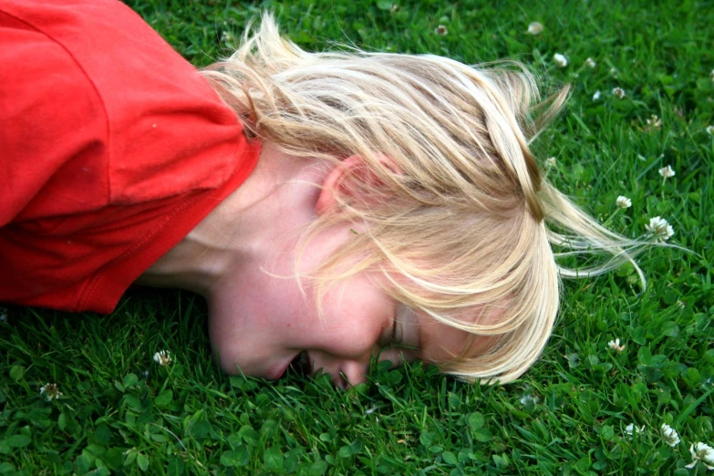 a young blonde child has her face in the grass