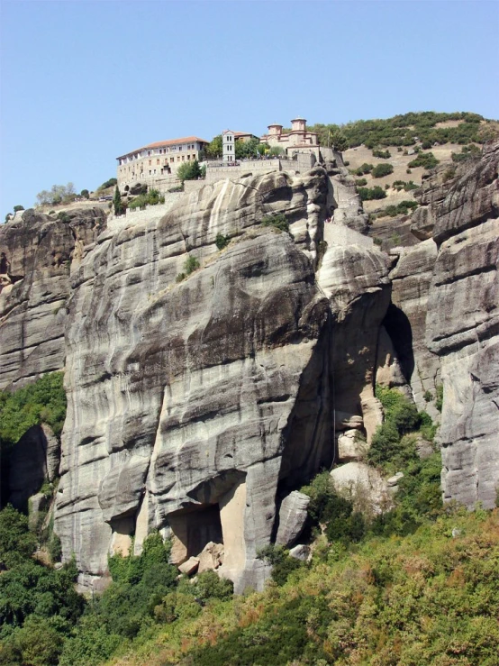 a tall rocky cliff with two trees at the base