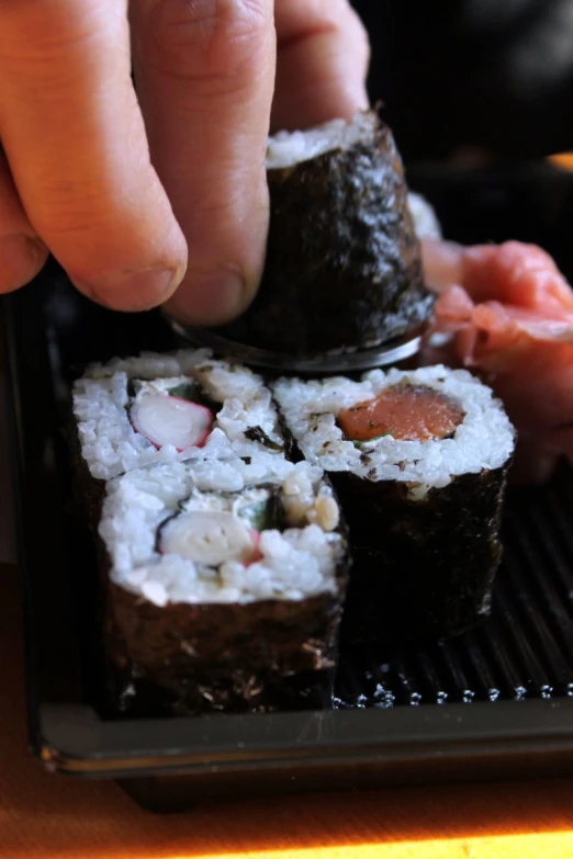 sushi in a container being picked up