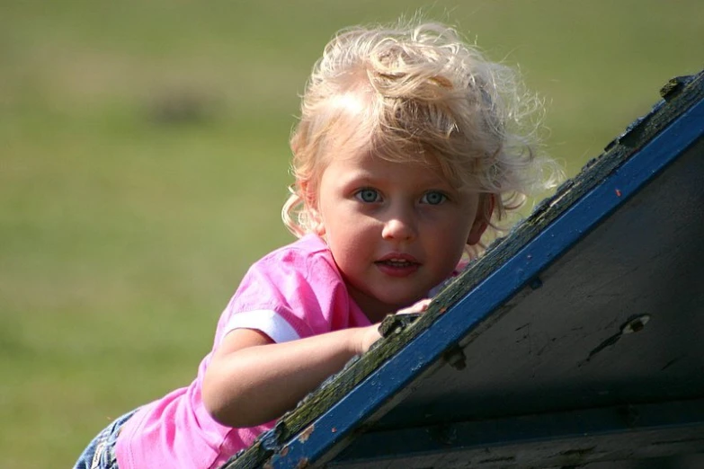 a little blond girl leaning on the side of a truck