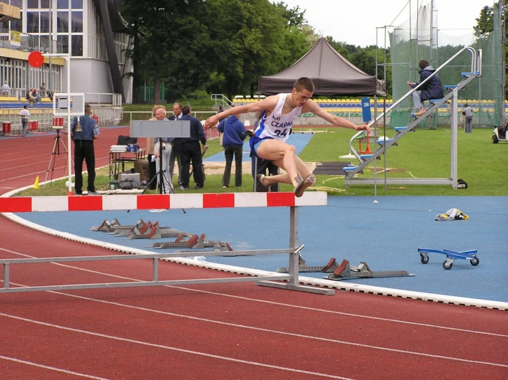 a boy in a blue shirt is jumping over an obstacle