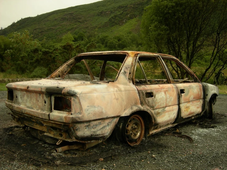 old car with rust from the engine sits in the dirt