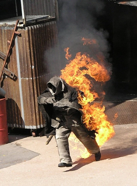 a person in a black coat standing in front of a yellow fire