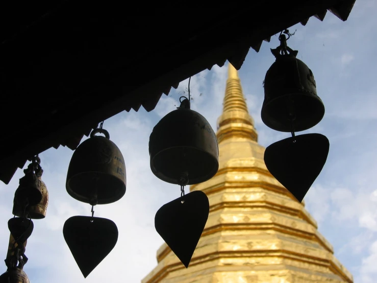 some bells hang from a gold steeple against a blue sky