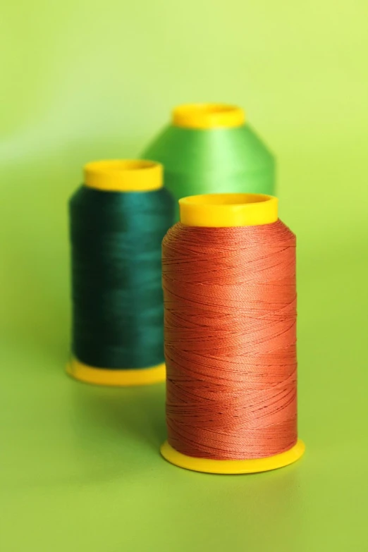 two spools of thread sitting on top of a green surface