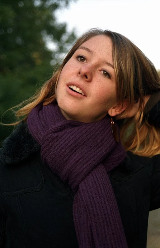 a woman with long brown hair wearing a purple scarf