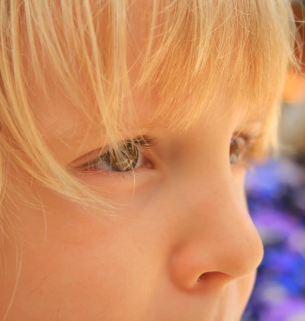 a close up of a child's eye with flowers in the background