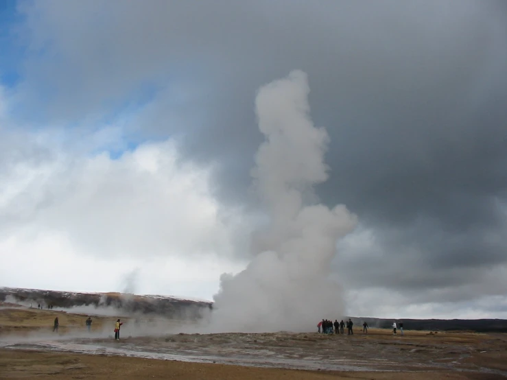 several people watching a geyser erupth into the air