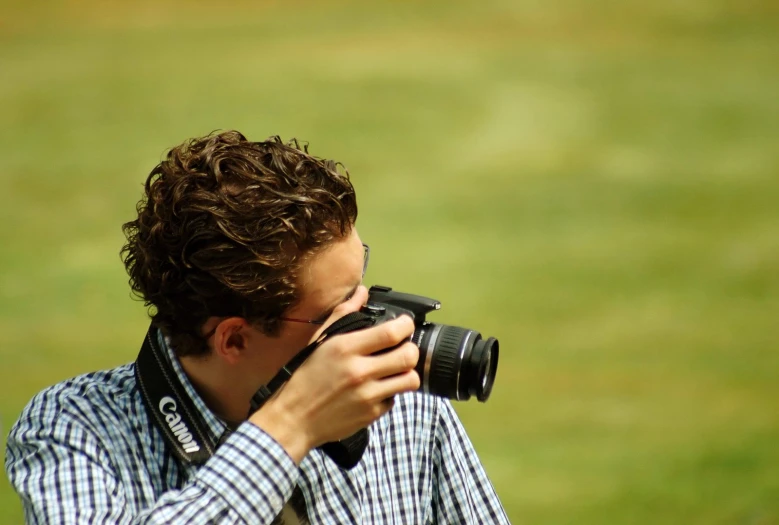 a man holding a camera taking a po in the field