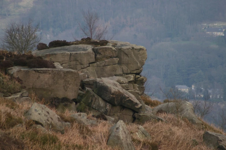 there is a rock formation in the middle of an area with dry grass