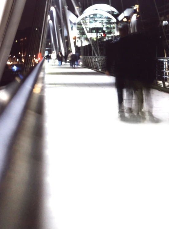 people walking down an enclosed walkway at night