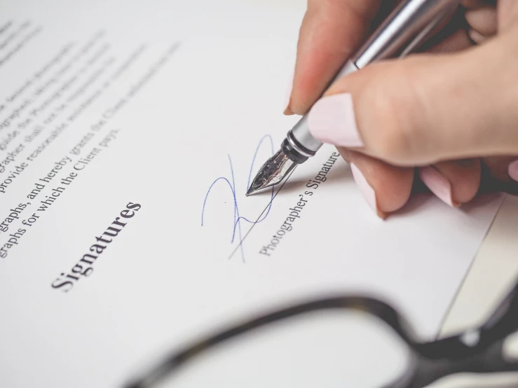 a hand signing a document with a pen