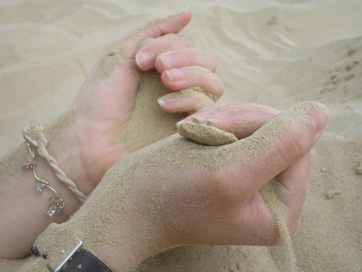 a sand covered foot is next to a person wearing some jewelry