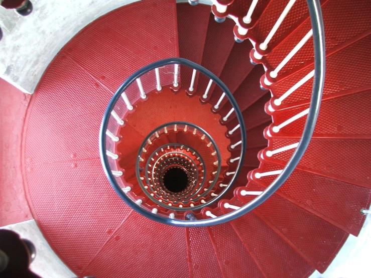 a spiral staircase with steel rails and red fabric