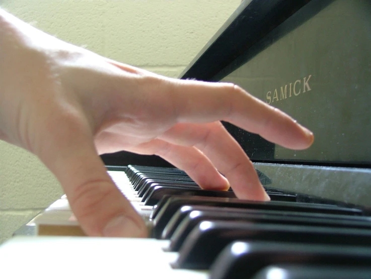 a hand is sitting at a piano near a keyboard