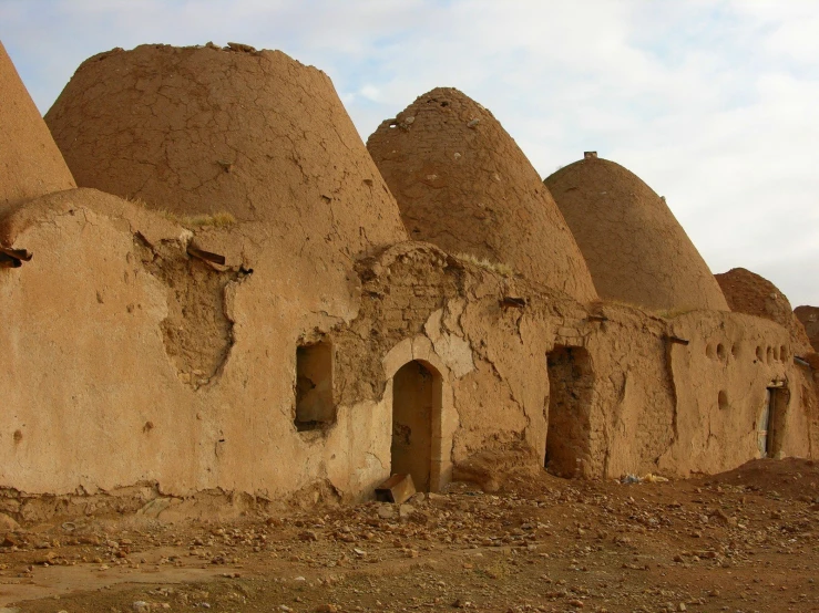 some brown buildings sitting on the side of a dirt road