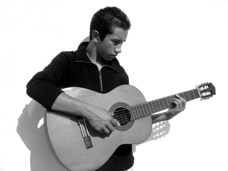 a young man in a black and white po holding an acoustic guitar