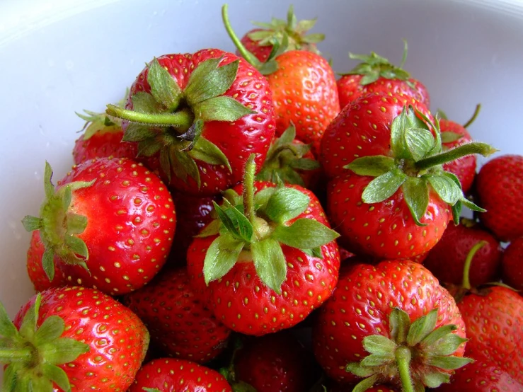 a big bowl of fresh strawberries with some leaves