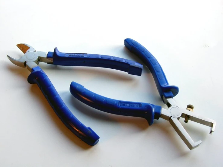 three pairs of pliers are sitting together on a white surface