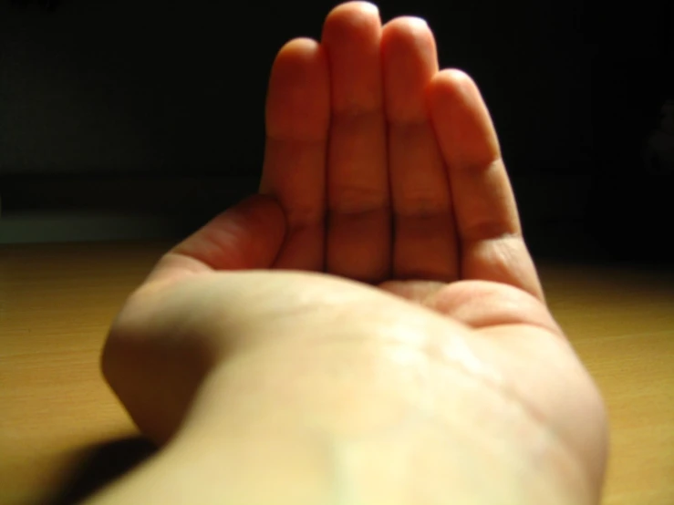 a person stretching their arm on a wooden table