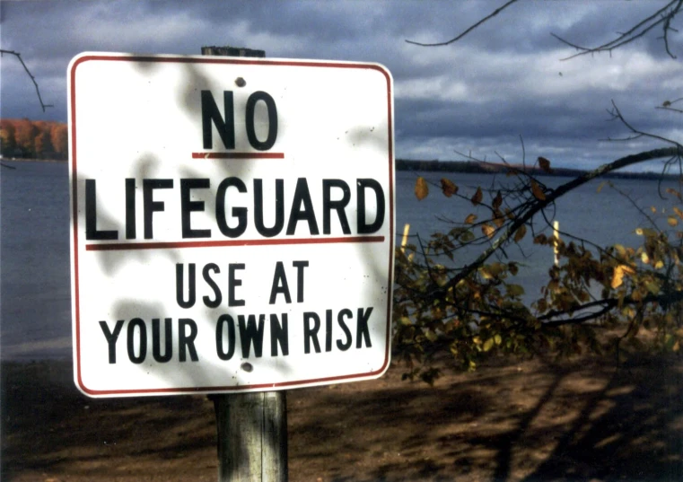 a no lifeguard sign next to a body of water