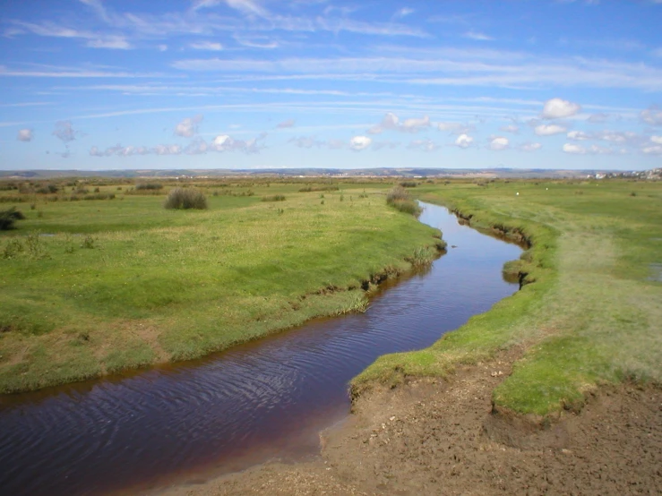 a wide body of water in the middle of green field