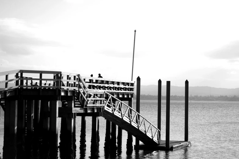 black and white image of pier on calm water