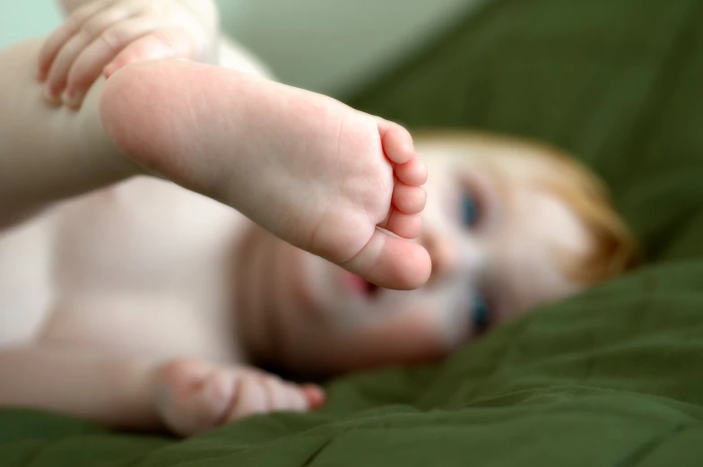 a toddler playing on his bed with a green comforter