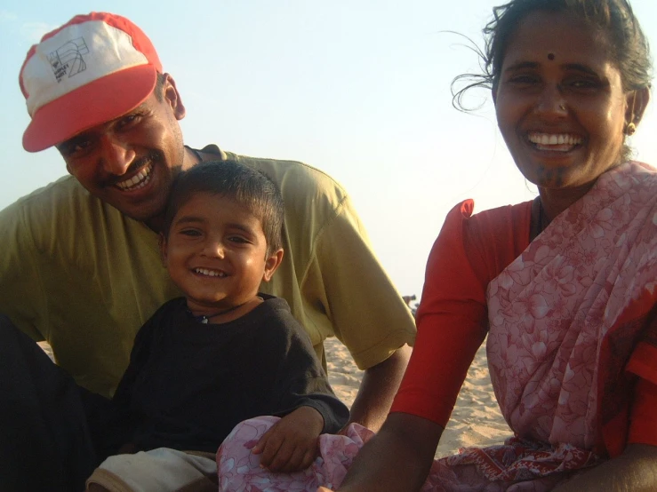 a woman sitting on top of a beach next to a small child