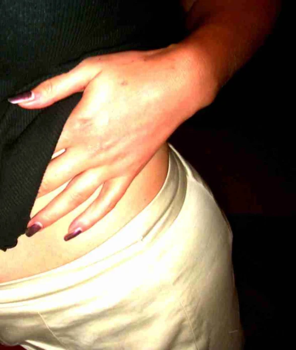 a woman with pink nails is holding her pants