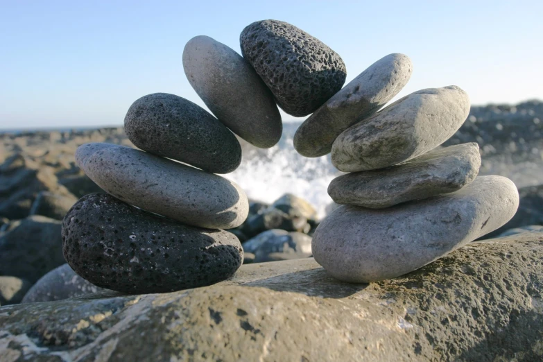 stacked pebbles on rocks on beach with ocean in background