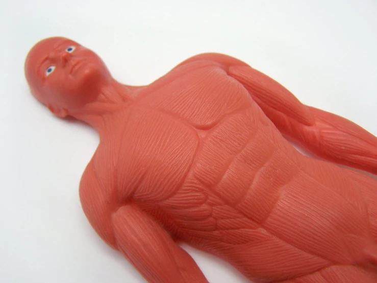 an orange plastic figurine laying down on a white surface