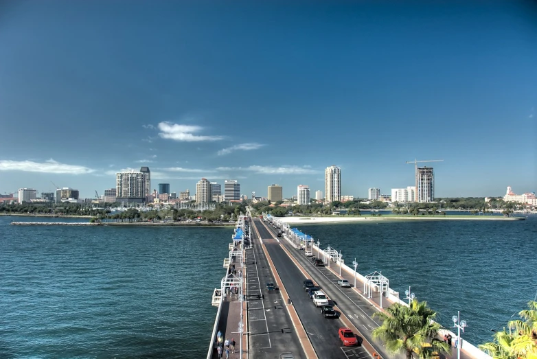 traffic driving over the ocean as tall buildings stand in the distance